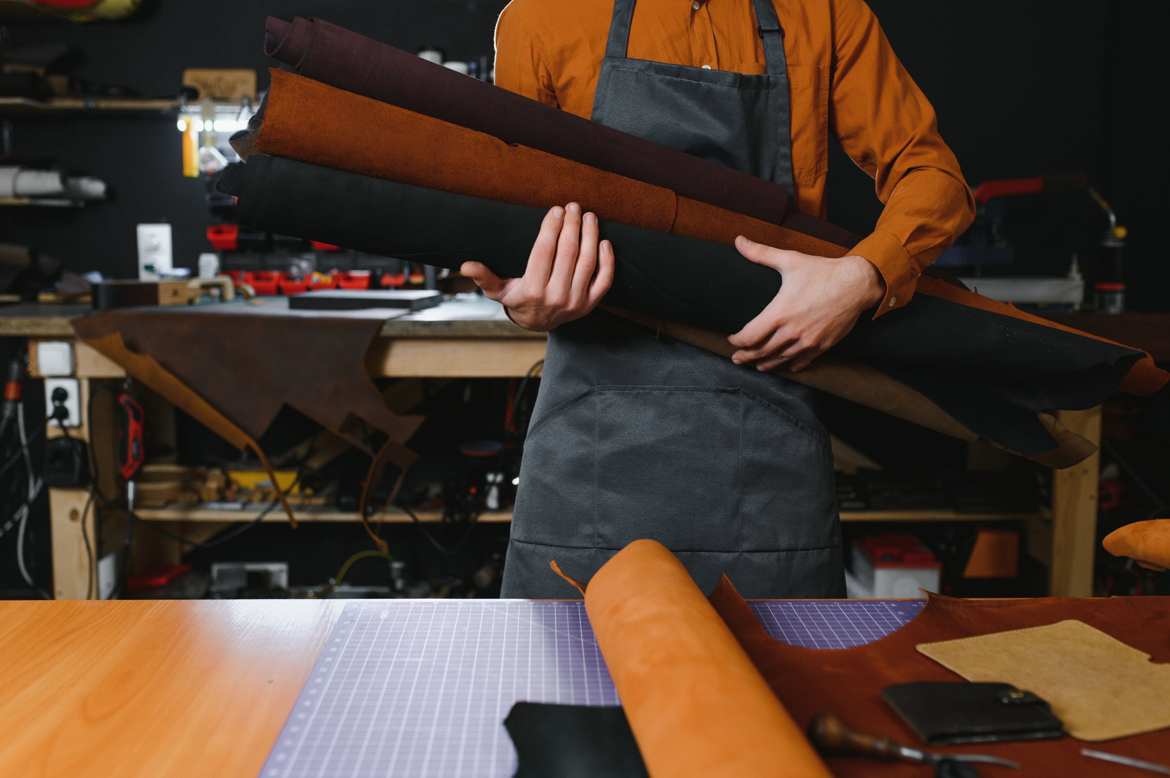 Craftsman with leather rolls and tools in leather studio